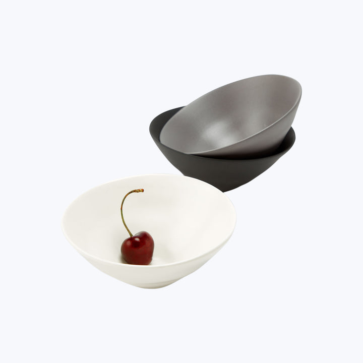 Minimalist composition with white bowl and ripe cherry.
