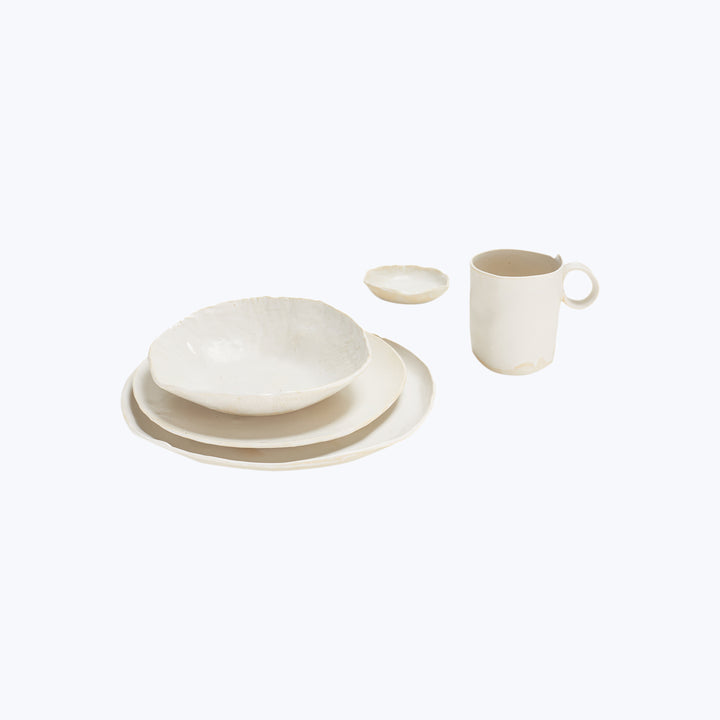 Minimalist white ceramic tableware set against plain white background.