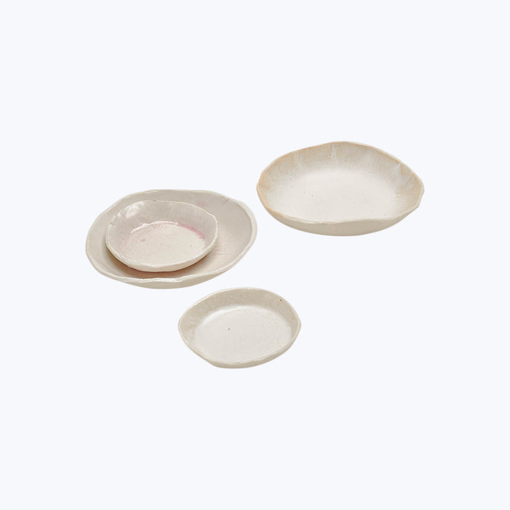 Handcrafted ceramic dishes in natural tones against white backdrop.