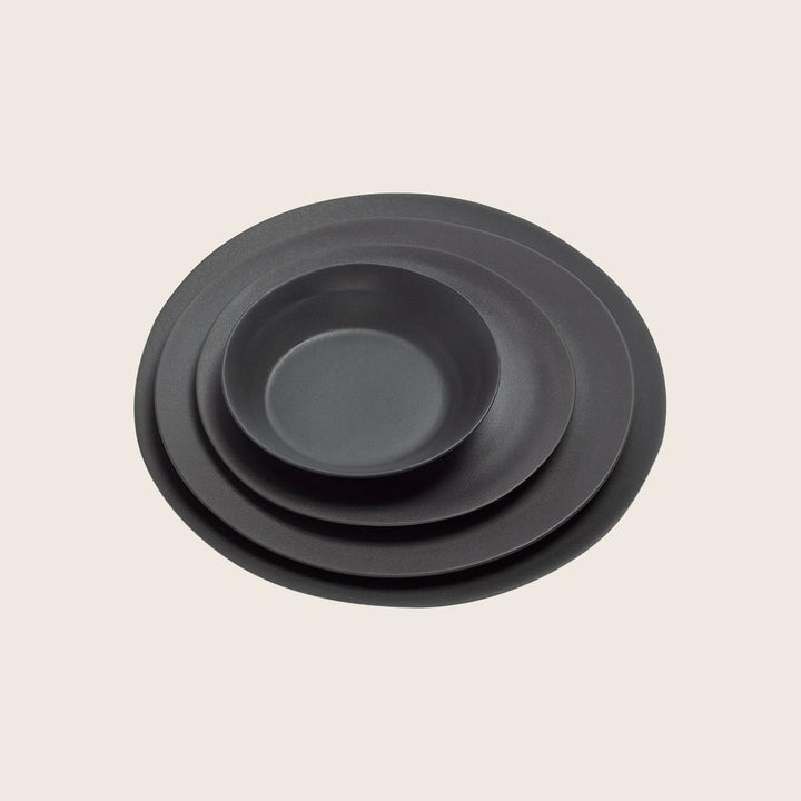 Minimalist black matte plates stacked by size on white background.