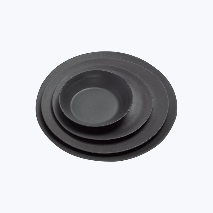 Minimalist black matte plates stacked by size on white background.