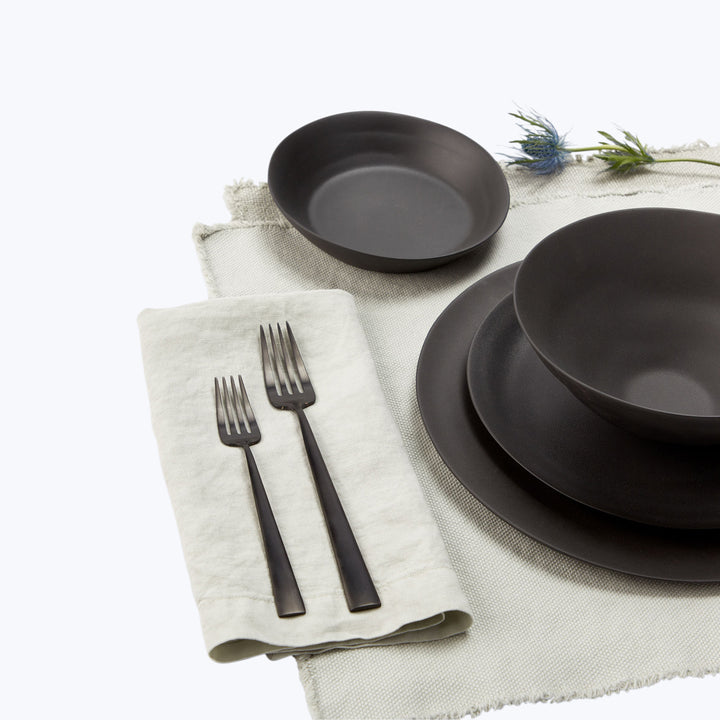Modern tableware set on light tablecloth creates elegant dining scene.