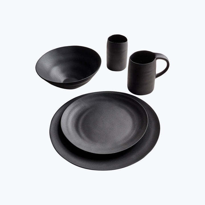 Modern black dinnerware set with matte finish on light background.