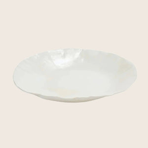Minimalist white ceramic plate with organic edge profile on display.