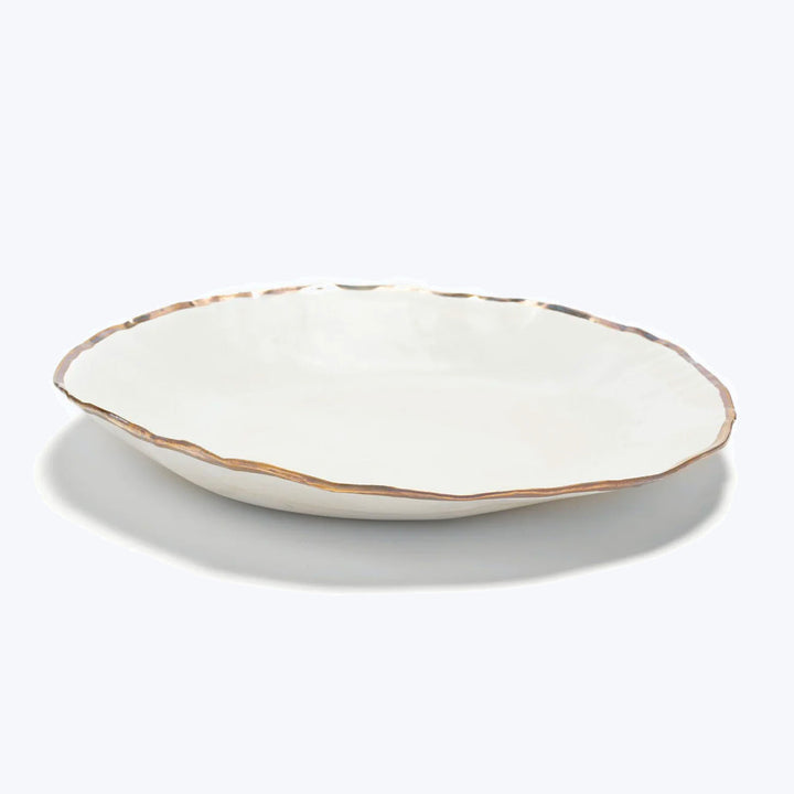 Handcrafted ceramic plate with wavy edge and rustic finish.
