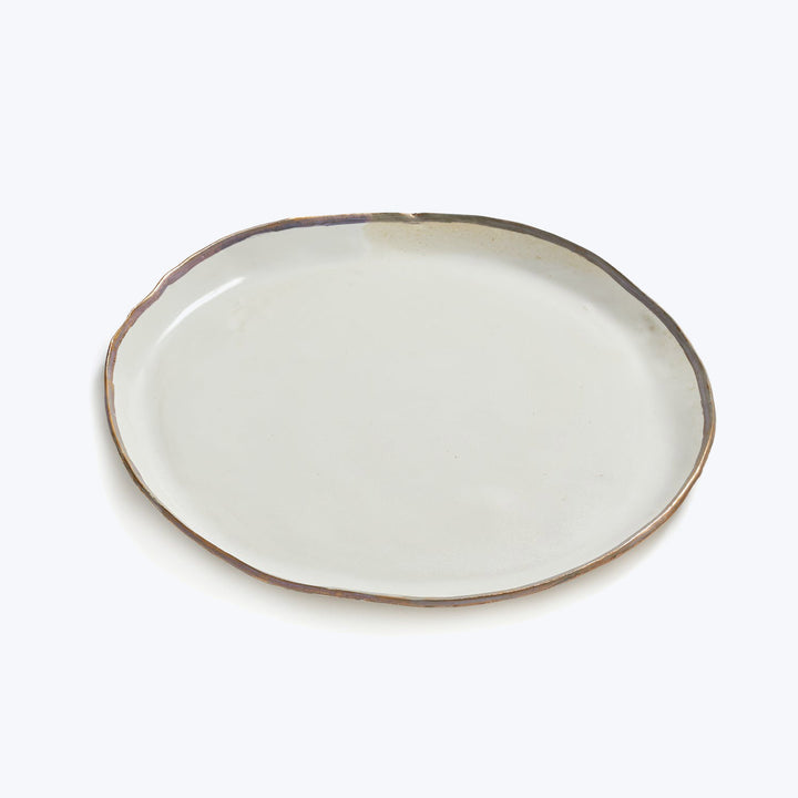 Simple ceramic plate with rustic rim on white background.