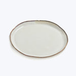 Simple ceramic plate with rustic rim on white background.