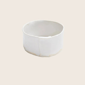 Minimalist white ceramic container with matte finish and irregularities.