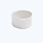 Minimalist white ceramic container with matte finish and irregularities.