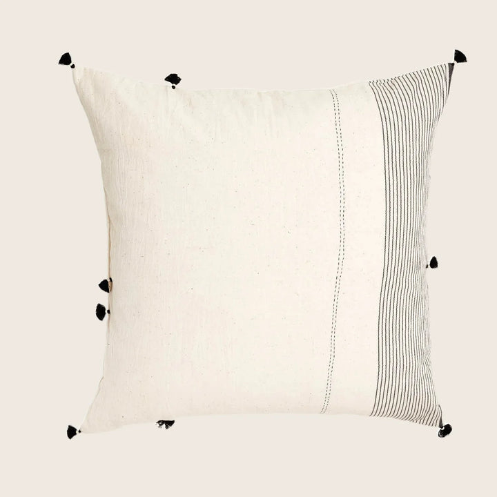 Square cream pillow with striped border and corner tassels.