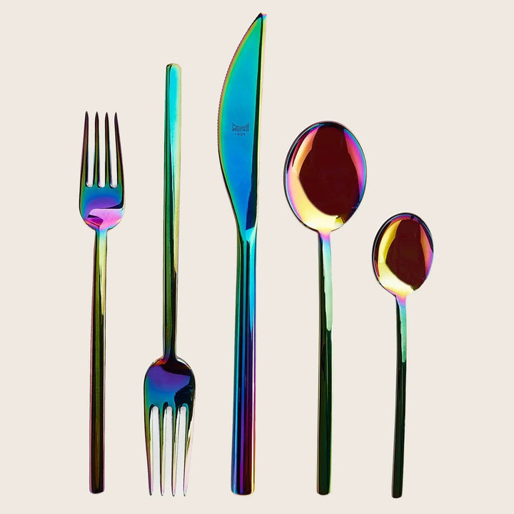 Set of iridescent cutlery with rainbow finish on white background.