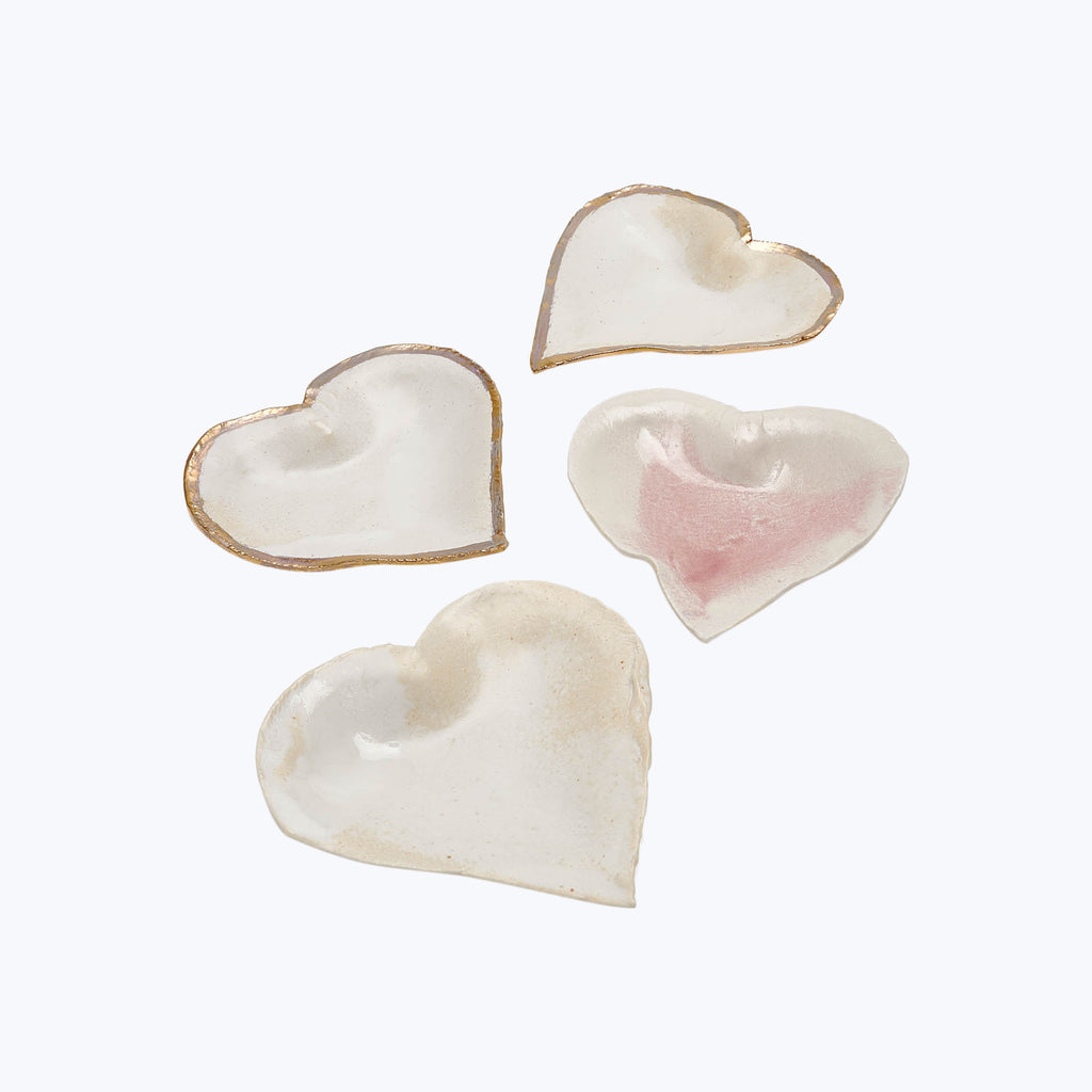 Four heart-shaped ceramic objects with varying glaze finishes on white.