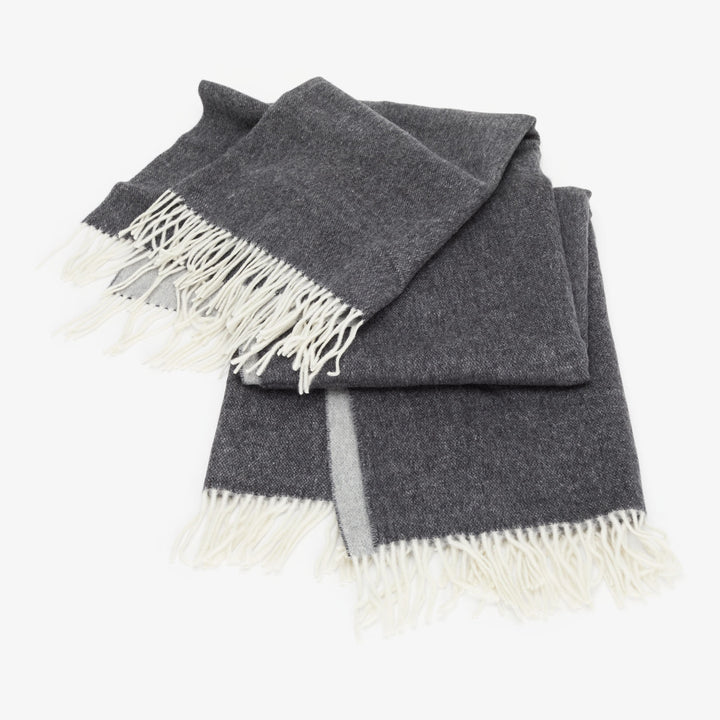 Dark grey woolen scarf with white tasseled fringes, light grey stripe.