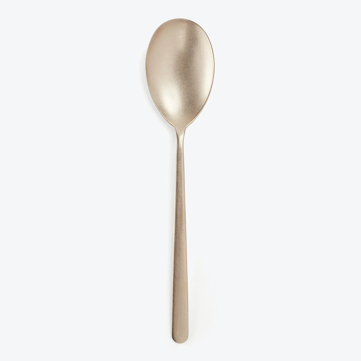 Elegant matte gold spoon on white background exudes modern luxury.