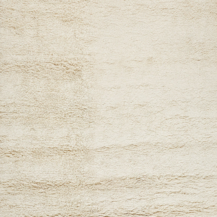 Close-up of a cream-colored, stucco-textured wall or fabric surface.