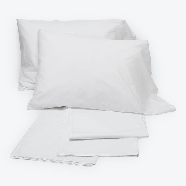 Plain white bed linens set with two pillowcases, folded neatly