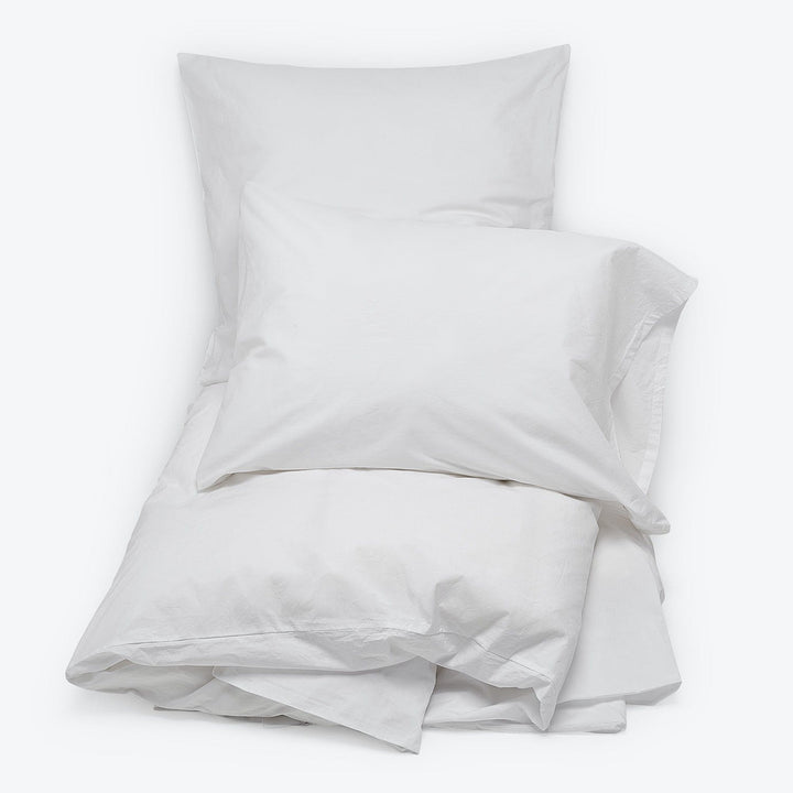Crisp white bedding set on minimalist background, serene and inviting.