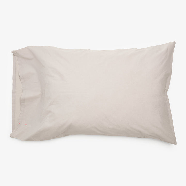 Minimalistic light-colored pillowcase with subtle red embroidery detail.