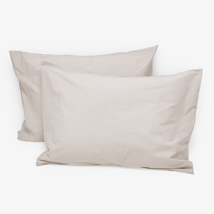 Two beige pillowcases on white background, simple design, fabric-textured.