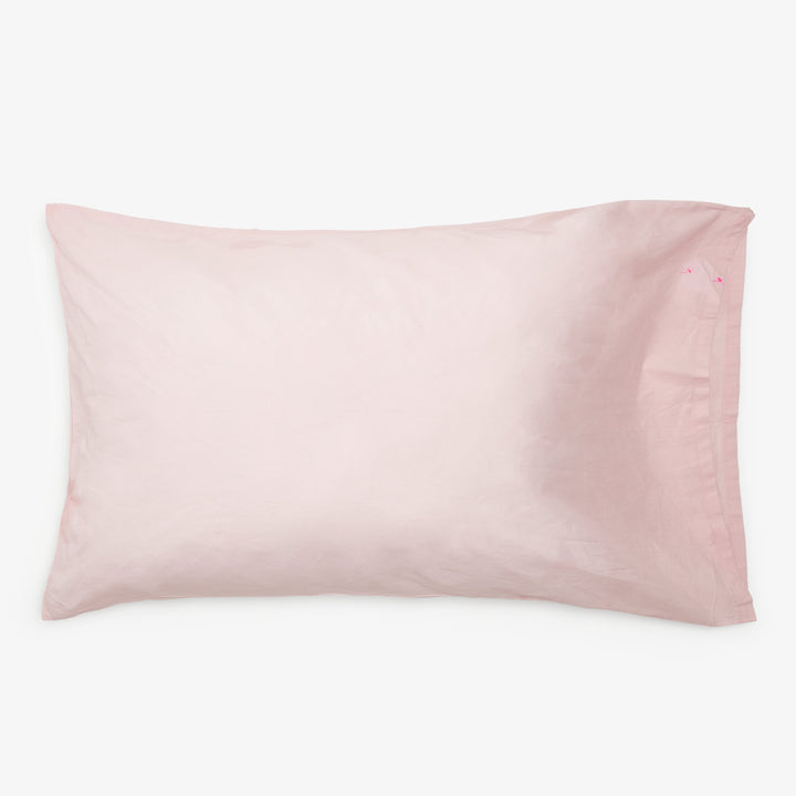 Pale pink pillowcase with slight texture on standard-size bed pillow.