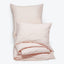 Pale pink bedding set on white background, showcasing softness and comfort.