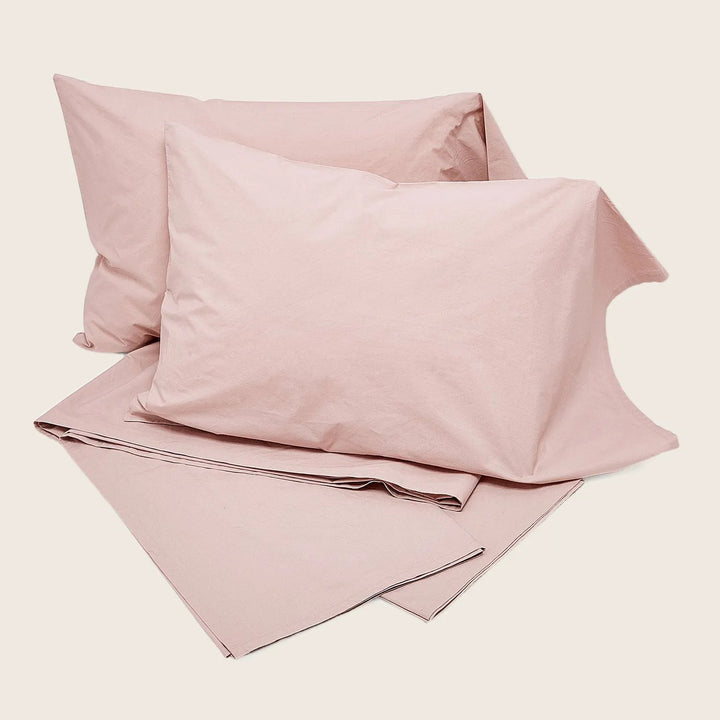 Pale pink bed linen set with dark piping detail, cozy texture.