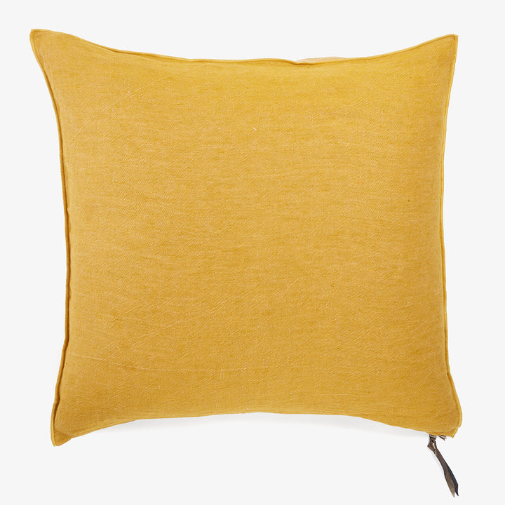 Square mustard yellow cushion with flange and black tag detail.