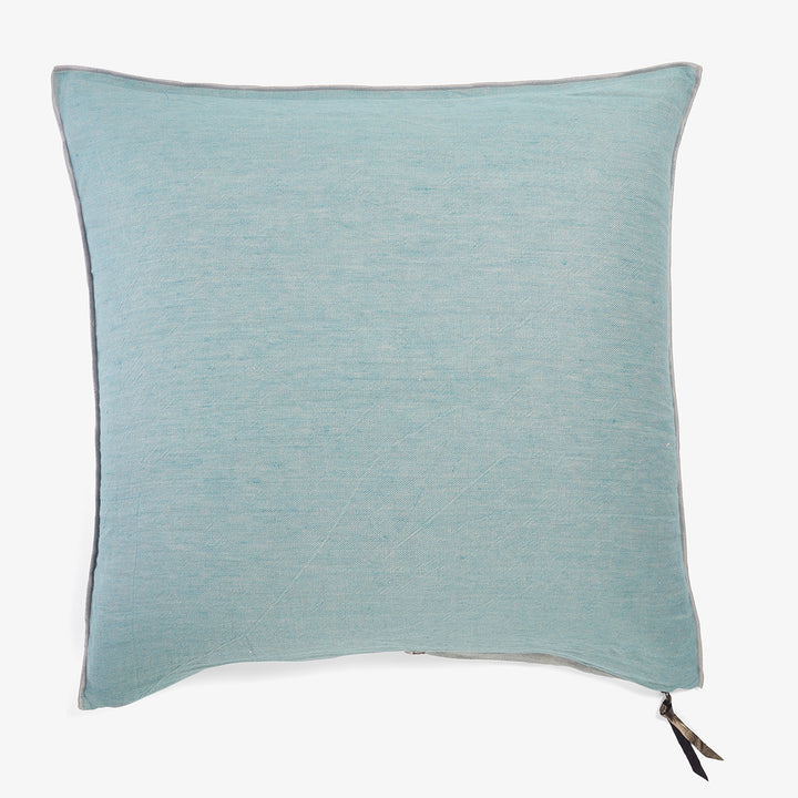 Square light blue linen pillow with black tassel detail.