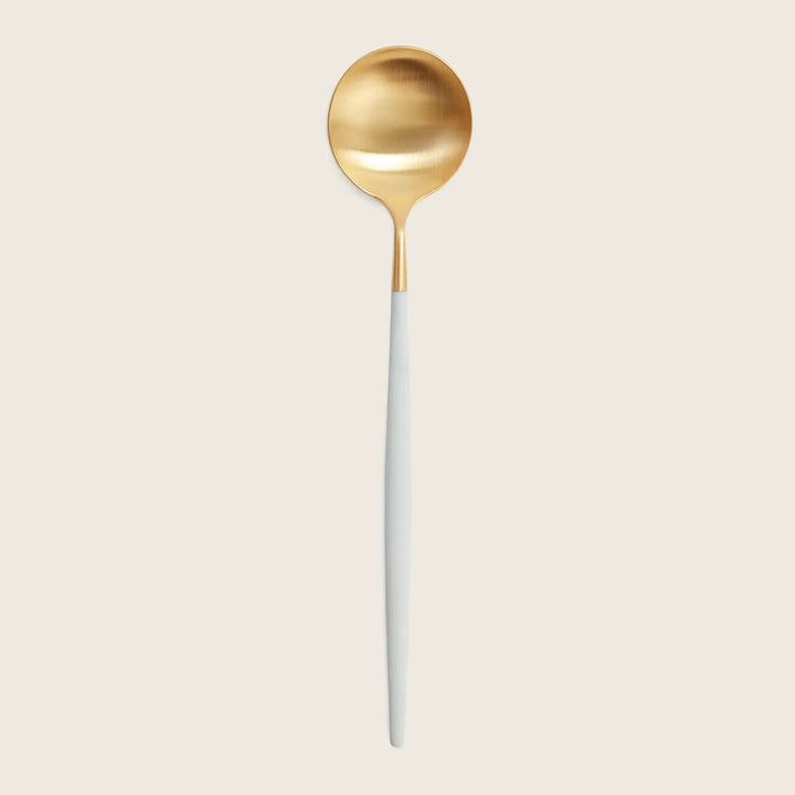 Modern gold and white spoon with long handle on white background.