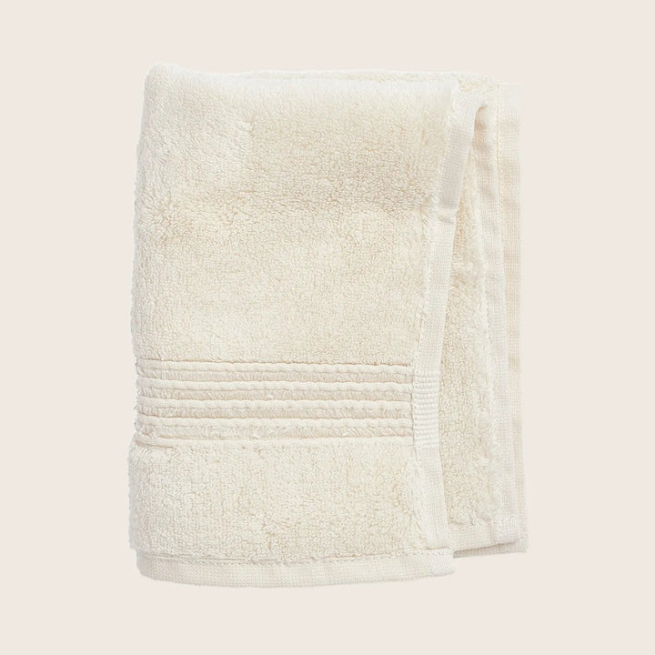 Soft and fluffy cream towel with decorative stripes on edge.