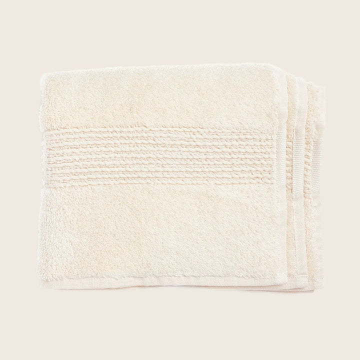 Folded cream towel with ribbed texture, stitched edges on white
