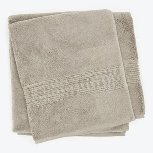 Folded plush beige towels with decorative patterned band stacked neatly.