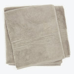 Folded plush beige towels with decorative patterned band stacked neatly.