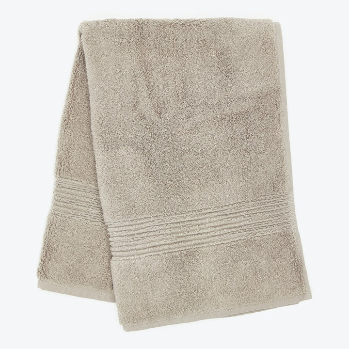 Soft beige bath towel with textured band for added grip.
