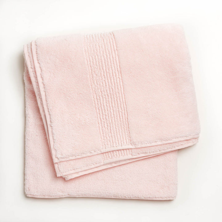 Soft, fluffy pale pink towel with textured border, cotton material.
