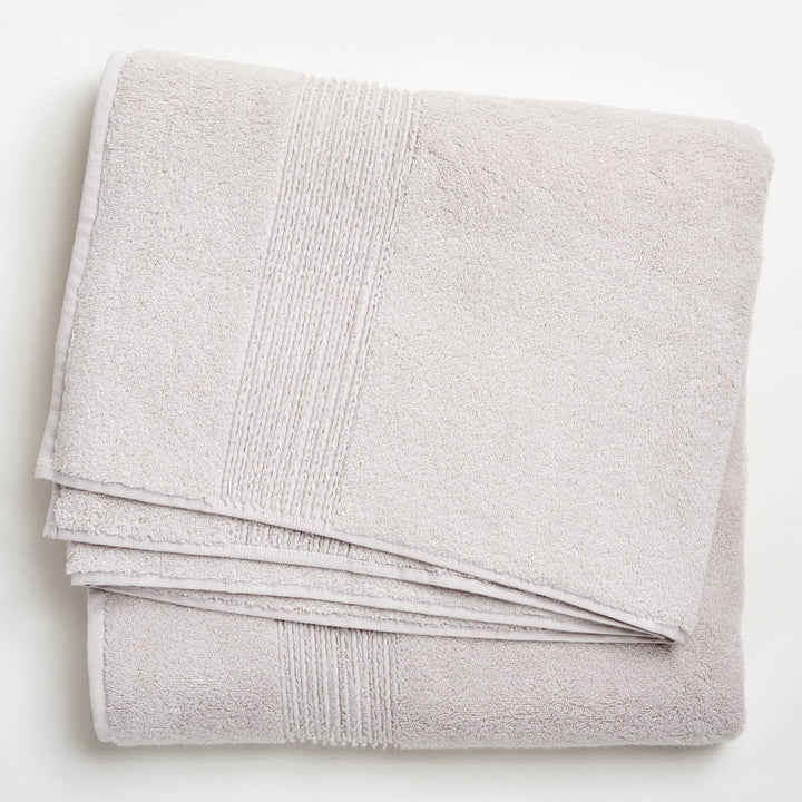 Soft, fluffy light-colored towel with decorative textured band lying flat.