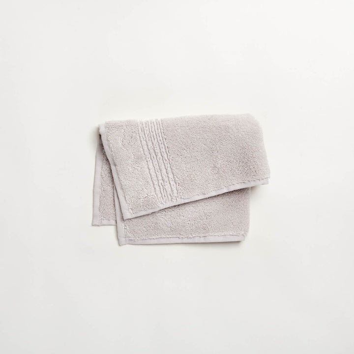 Neatly folded light gray towel with textured pattern on white background.