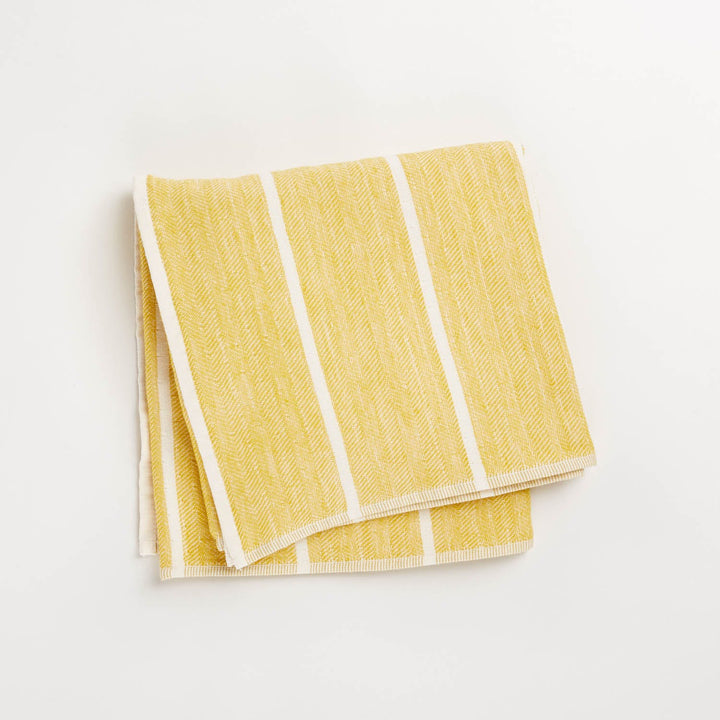 Folded yellow and white striped dish towel on white background.
