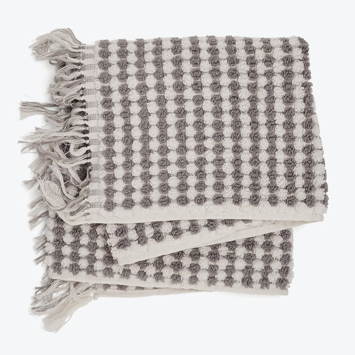 Checkered textile item with fringes in grey and white colors.