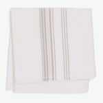 Neatly folded white towel with vertical stripe design in tan