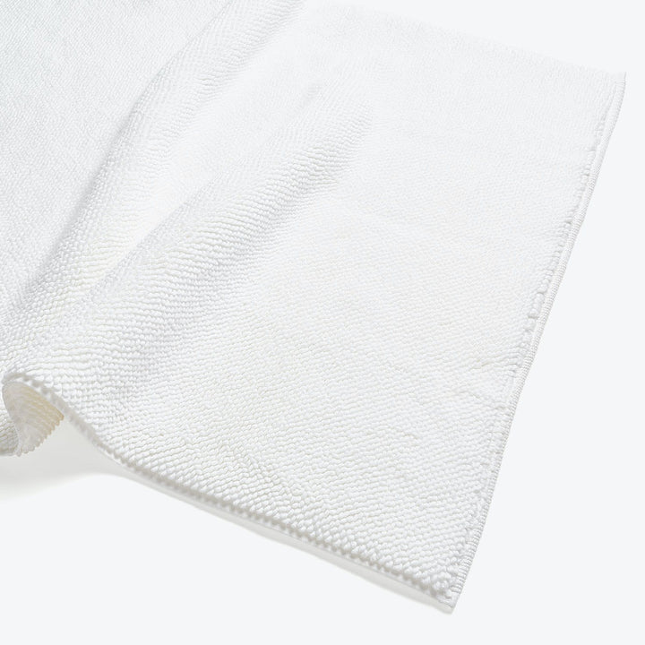White textured fabric laid flat, creating soft shadow, folded over.