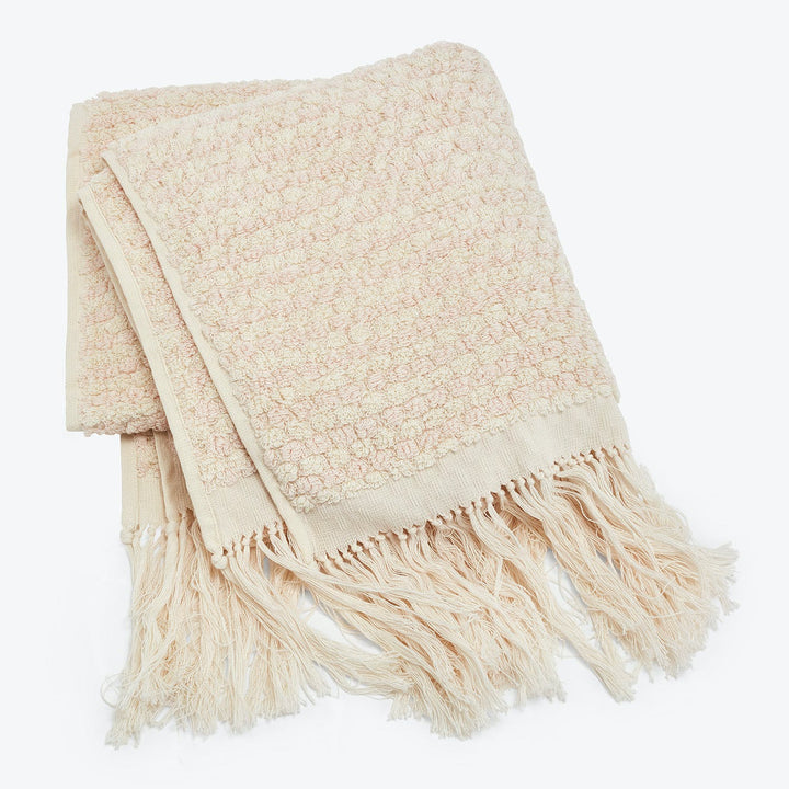 Cozy pink-beige throw blanket with fringe detailing, textured design.