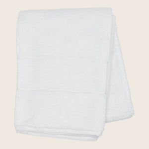 Soft white bath towel with decorative band on white background.