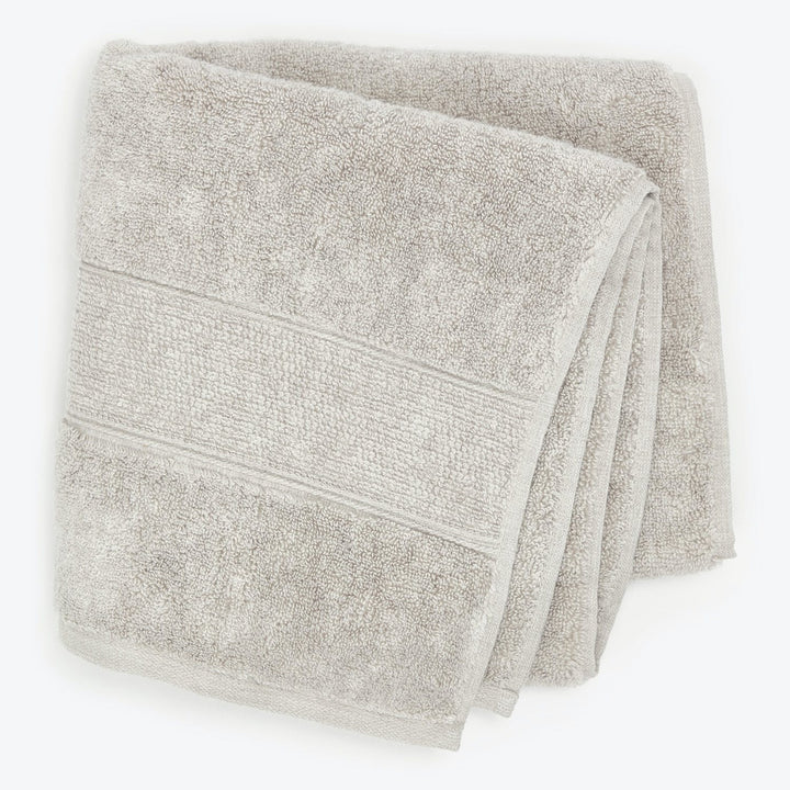 Two soft, plush bath towels with decorative trim on top.