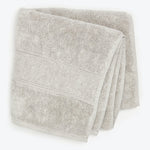 Two soft, plush bath towels with decorative trim on top.