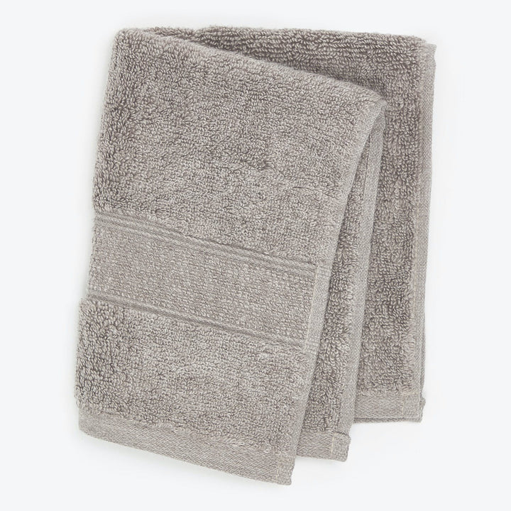 Neatly folded gray towel with textured design on light background.