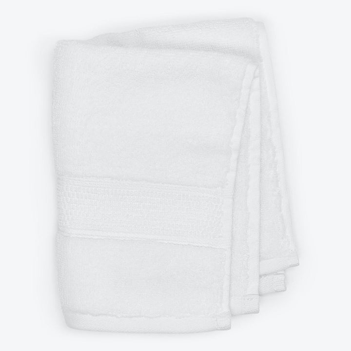 Plush white towel with decorative border on white background.