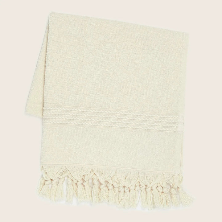 Cream textile with fringe and decorative pattern; soft and stylish.