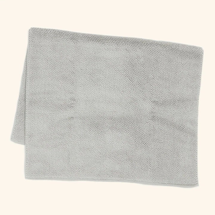 Soft, plush light grey towel neatly folded on white background.