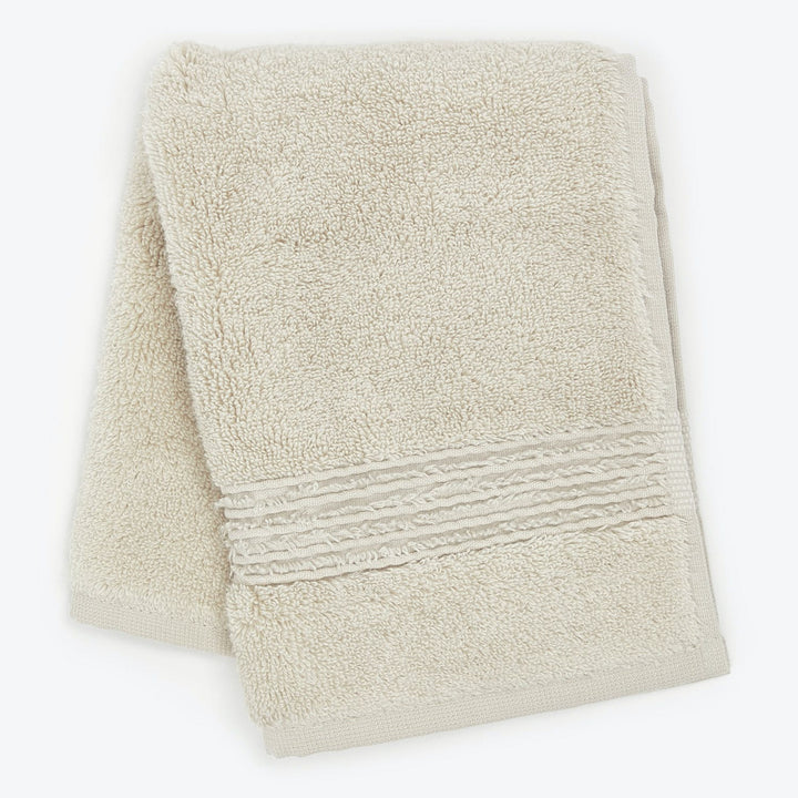 Soft, fluffy terrycloth towel in cream color with decorative band.